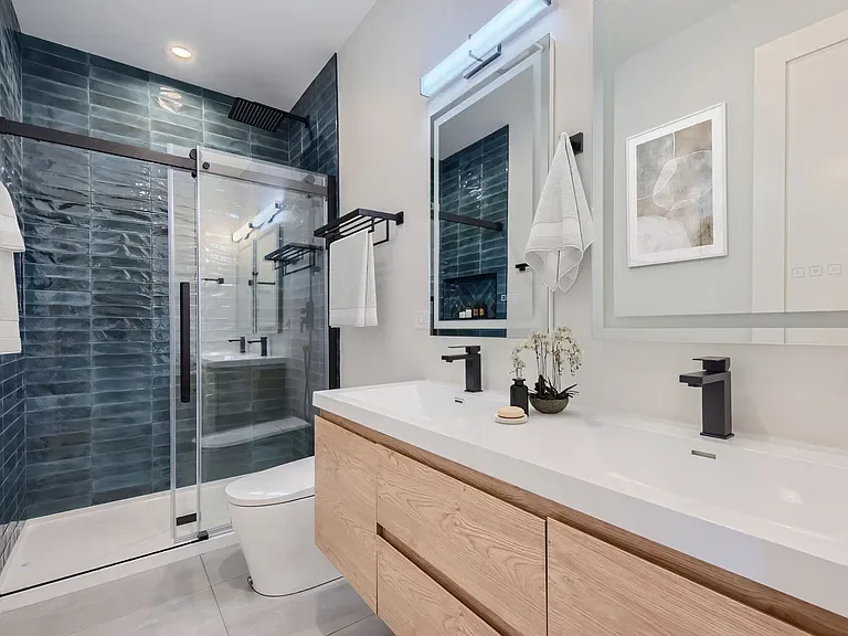 Finished contemporary bathroom with blue tile shower and natural wood vanity